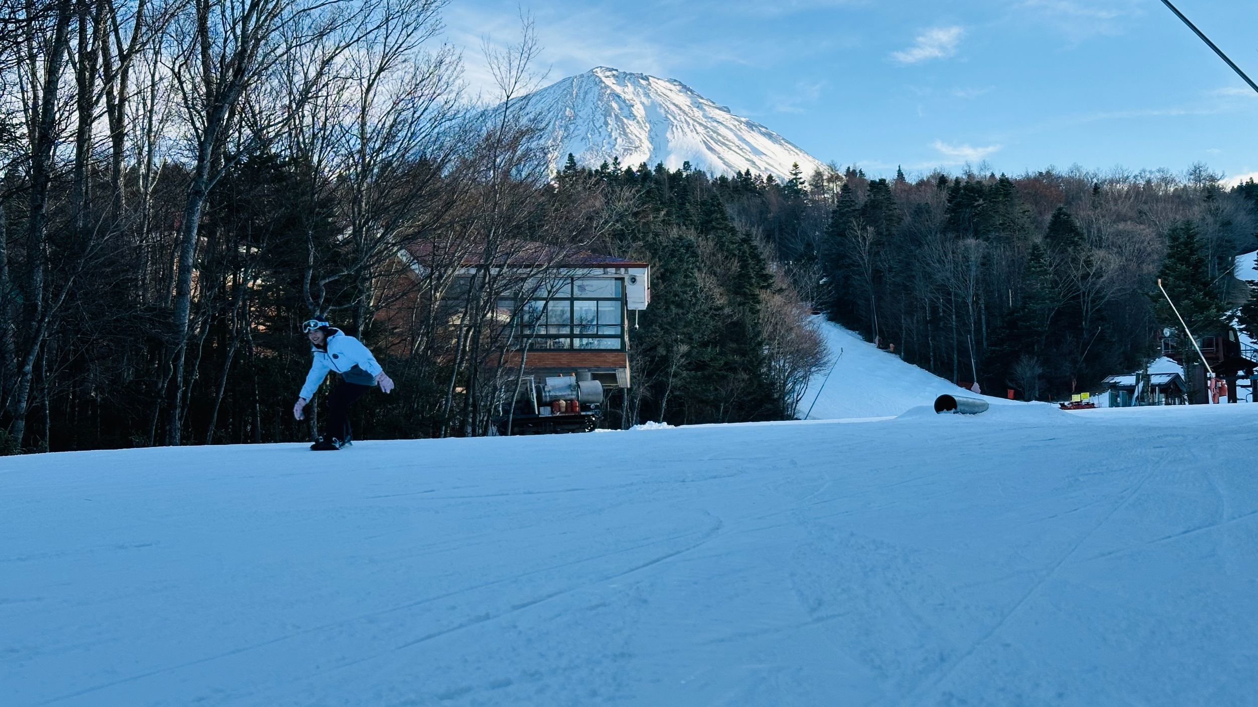 富士山を正面に望むゲレンデをスノーボードで滑る人